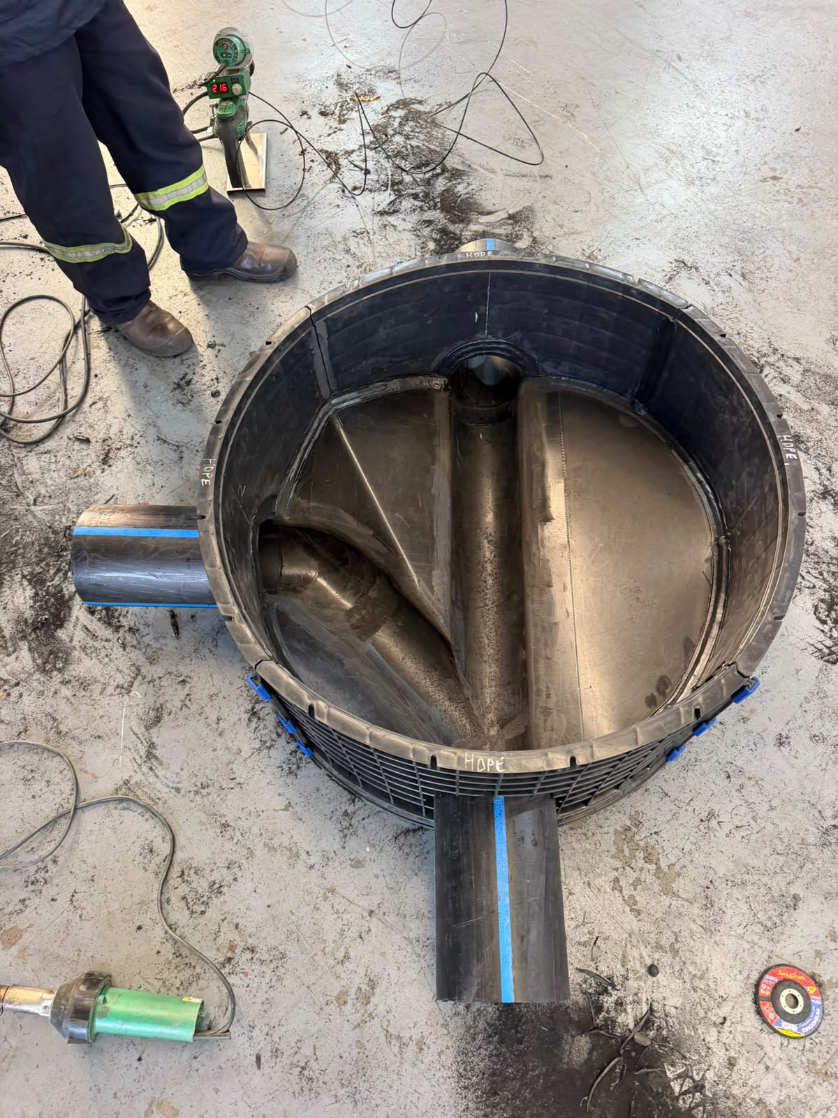 Custom fabricated HDPE manhole with benched base, viewed from above during workshop assembly